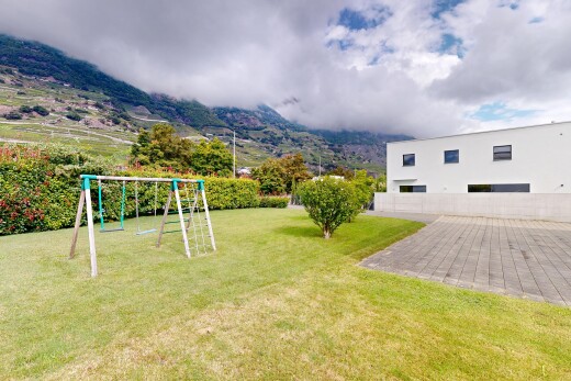 outdoor house with a playground, a lawn, and stucco siding