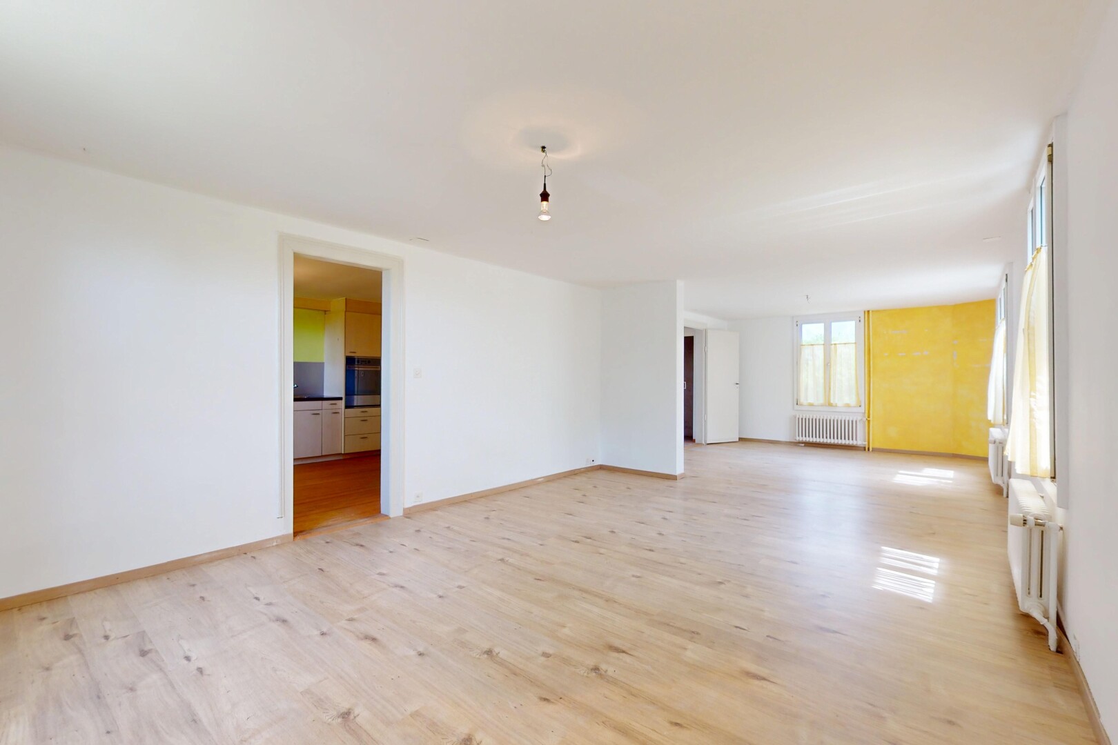 pièce vide avec radiateur, sol en finition bois, wood finish floor, inside property, et lumière naturelle