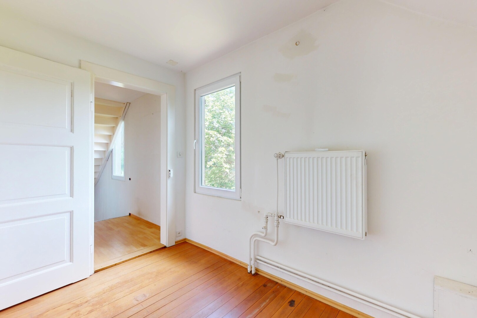pièce vide avec radiateur, sol en finition bois, wood finish floor, lumière naturelle, et natural light