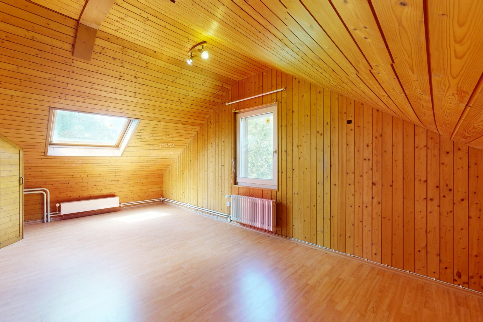 pièce vide avec radiateur, plafond voûté, vaulted ceiling, sol en finition bois, et wood finish floor