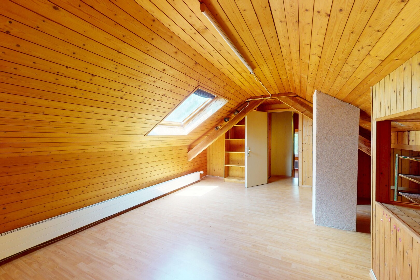 pièce vide avec radiateur à plinthe, pièce supplémentaire, puits de lumière, sol en finition bois, et wood finish floor
