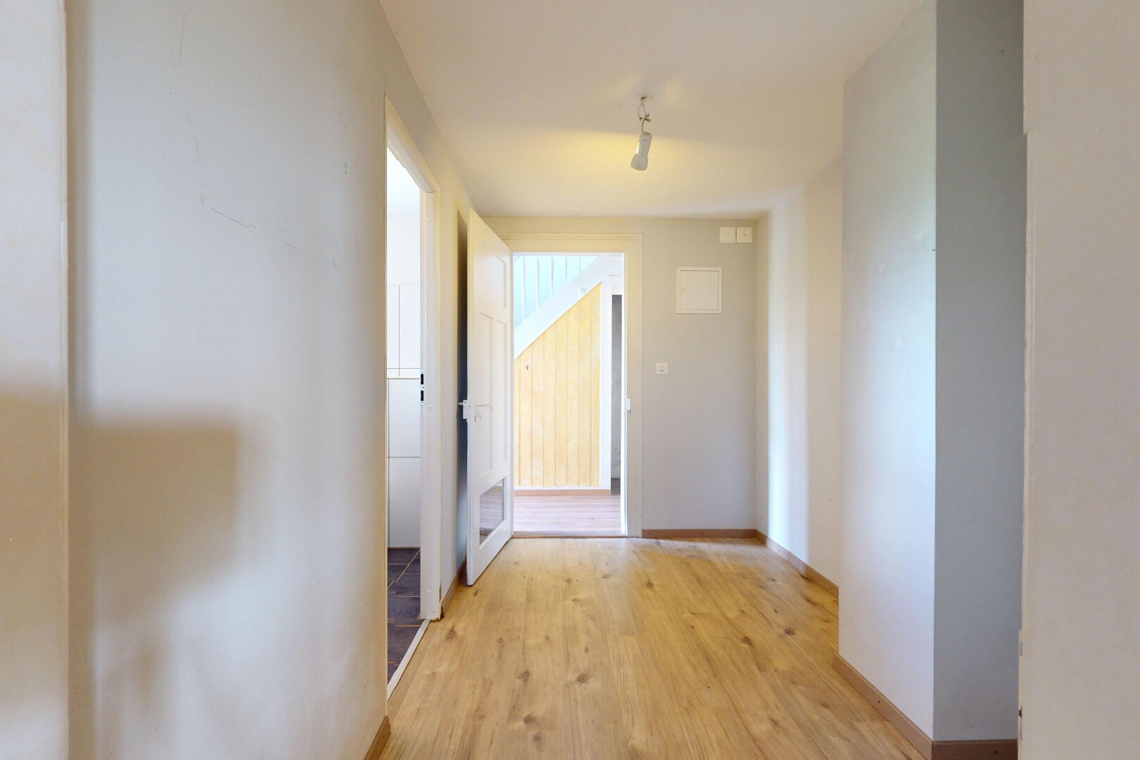 couloir avec cloison sèche, drywall, inside property, sol en finition bois, et wood finish floor