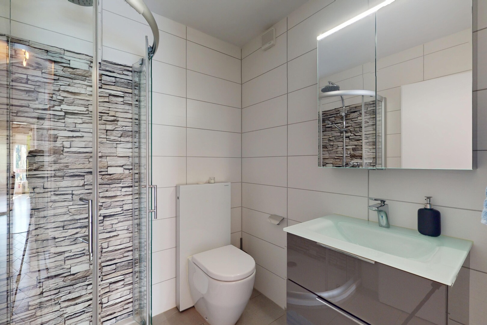 salle de bains avec mur en carrelage, tile wall, inside property, lavabo (ou coiffeuse selon le contexte), et douche
