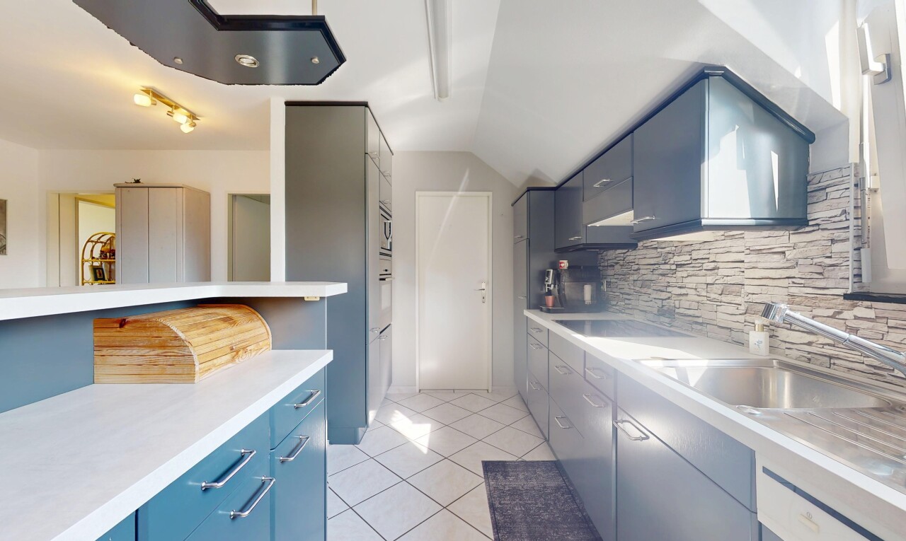 cuisine avec plaque de cuisson, armoires bleues, dosseret, backsplash, et sol en carrelage