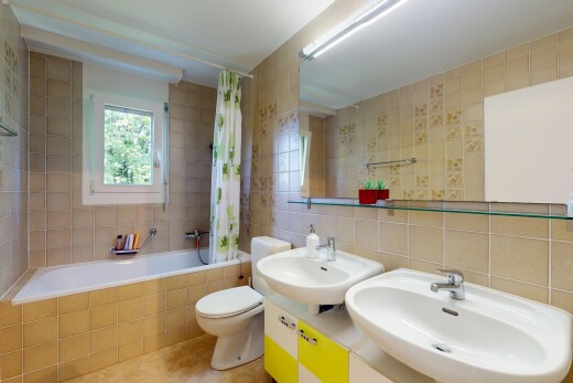 salle de bains avec évier, mur en carrelage, tile wall, inside property, et lumière naturelle