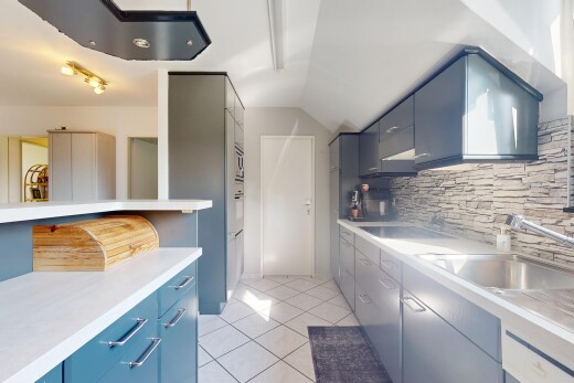 cuisine avec plaque de cuisson, armoires bleues, dosseret, backsplash, et sol en carrelage