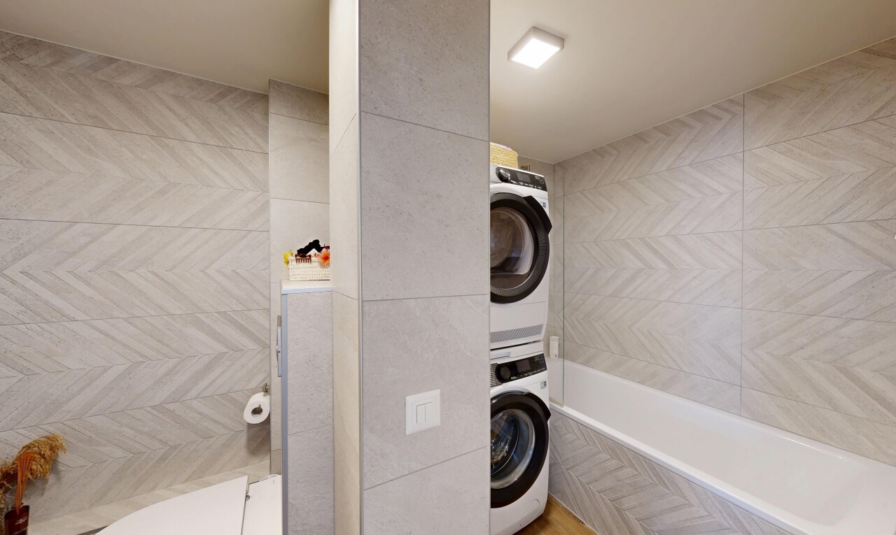 laundry area featuring stacked washer / drying machine and tile walls