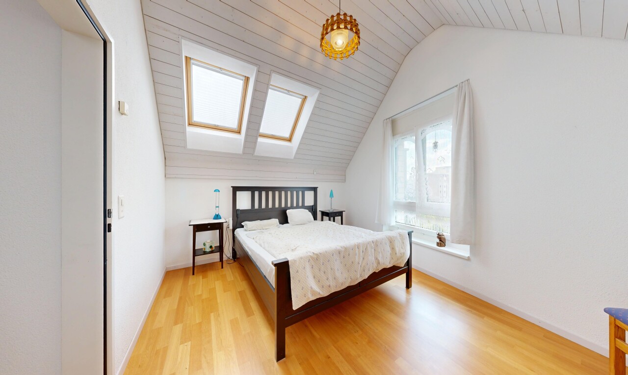 zimmer / schlafzimmer mit wood finish floor, holzfußboden, pendelleuchte, vaulted ceiling, und dachschräge