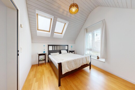 zimmer / schlafzimmer mit wood finish floor, holzfußboden, pendelleuchte, vaulted ceiling, und dachschräge