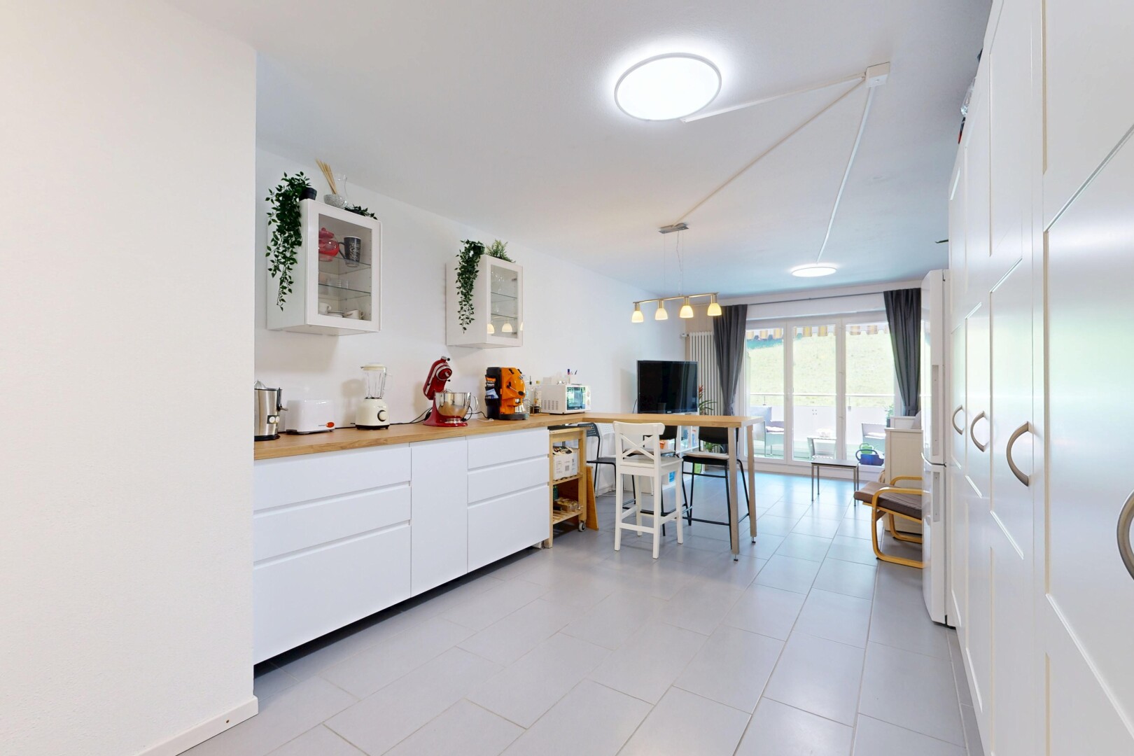 cuisine avec armoires blanches, white cabinets, light countertops, inside property, et éclairage suspendu