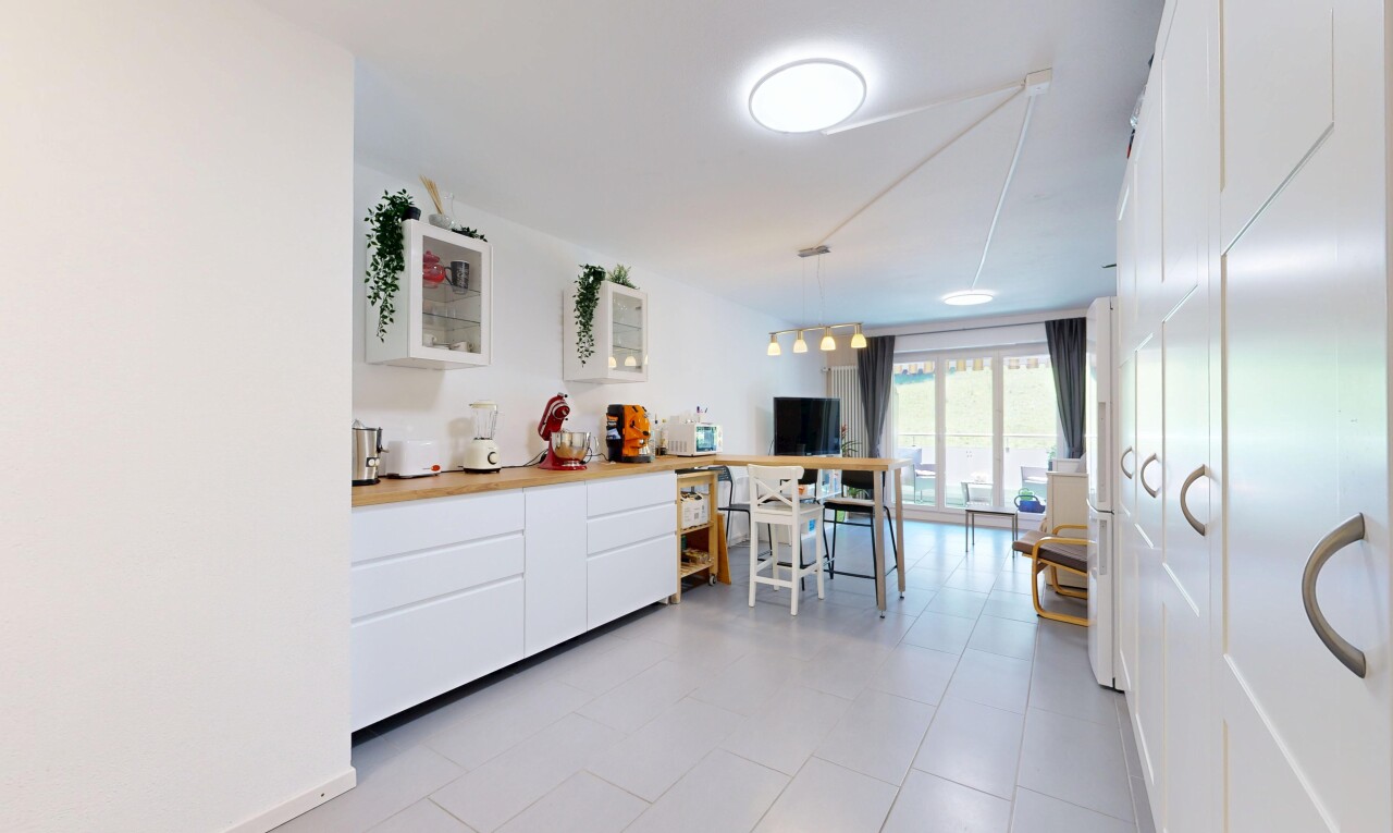 cuisine avec armoires blanches, white cabinets, light countertops, inside property, et éclairage suspendu