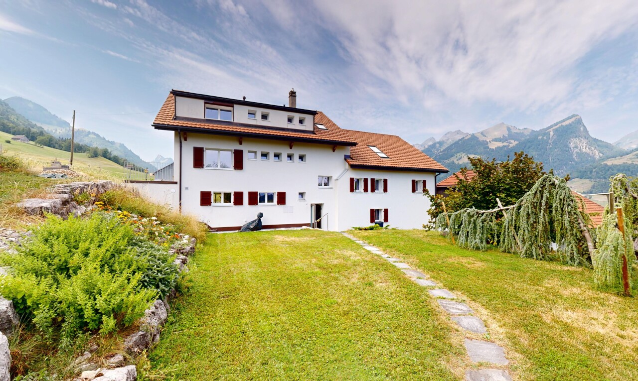 outdoor house featuring a yard, a chimney, a tiled roof, and a mountain view