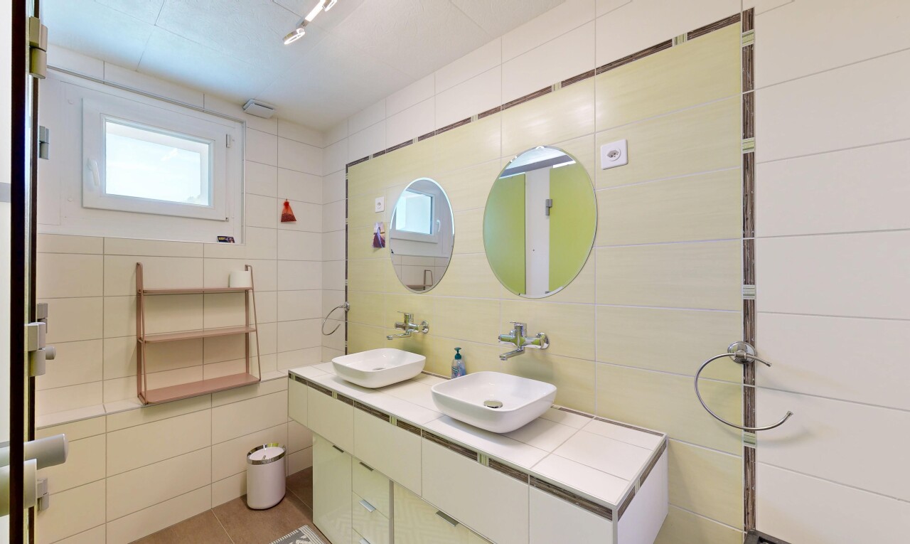 full bathroom with tile walls and double vanity
