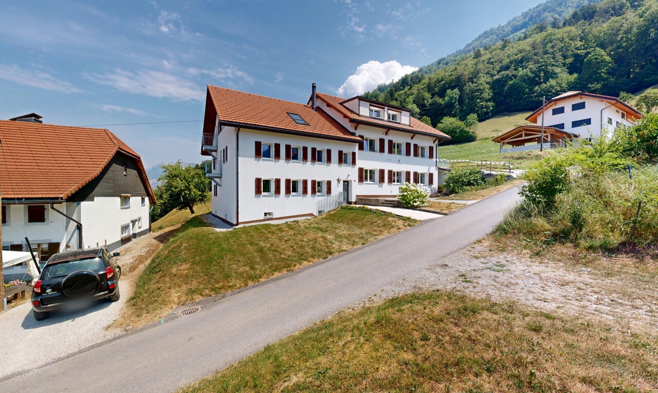 view of property featuring a lawn and a tile roof