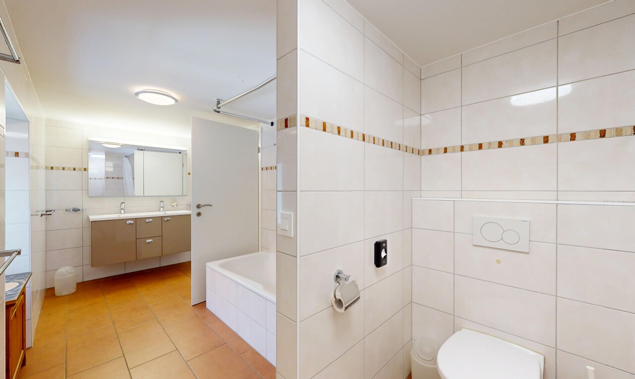 bathroom featuring tile walls, double vanity, tiled shower / bath combo, and light tile patterned flooring