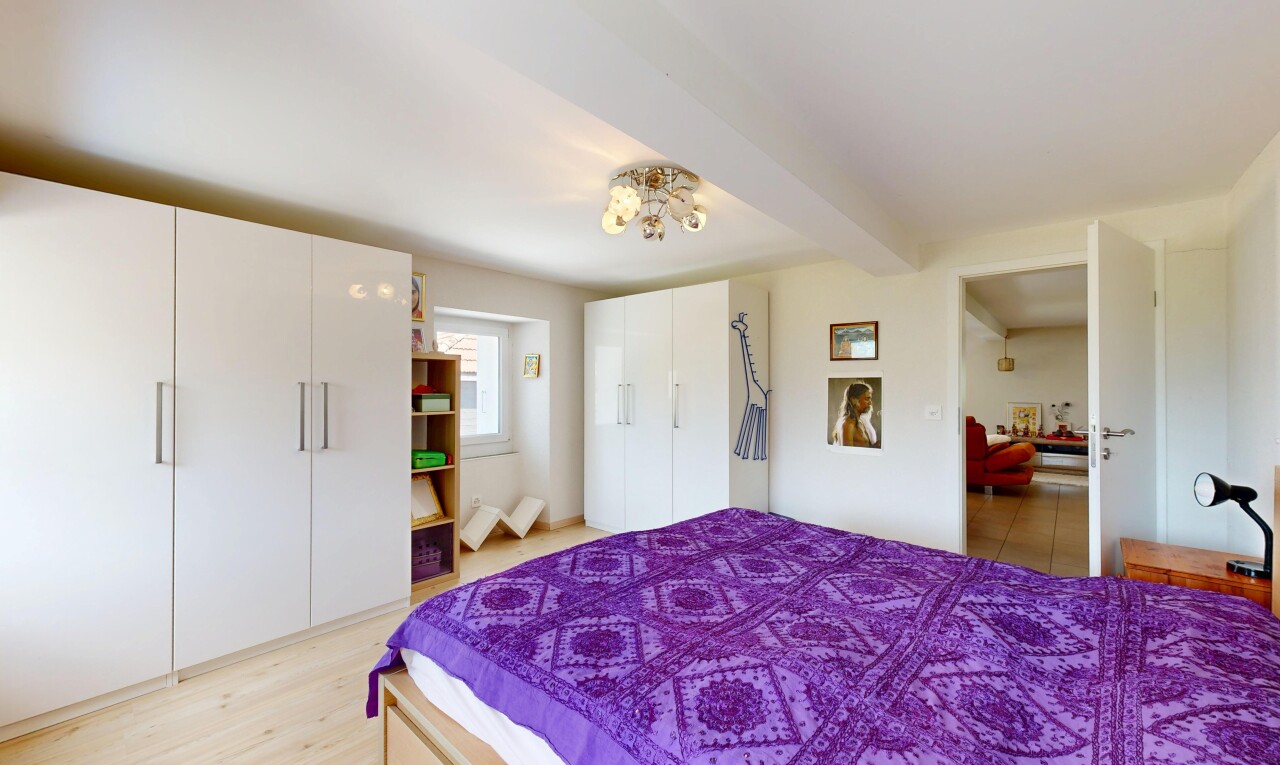 room / bedroom featuring a closet, beamed ceiling, and light wood finished floors
