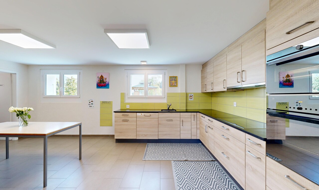 kitchen featuring light wood finish cabinetry, dark countertops, double wall oven, and black electric cooktop