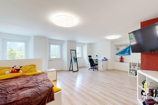 chambre avec lumière naturelle, télévision, drywall, cloison sèche, et wood finish floor