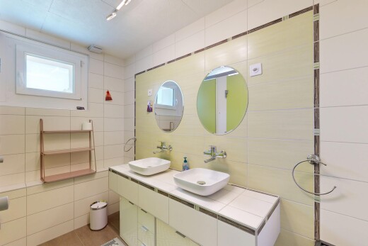 full bathroom with tile walls and double vanity
