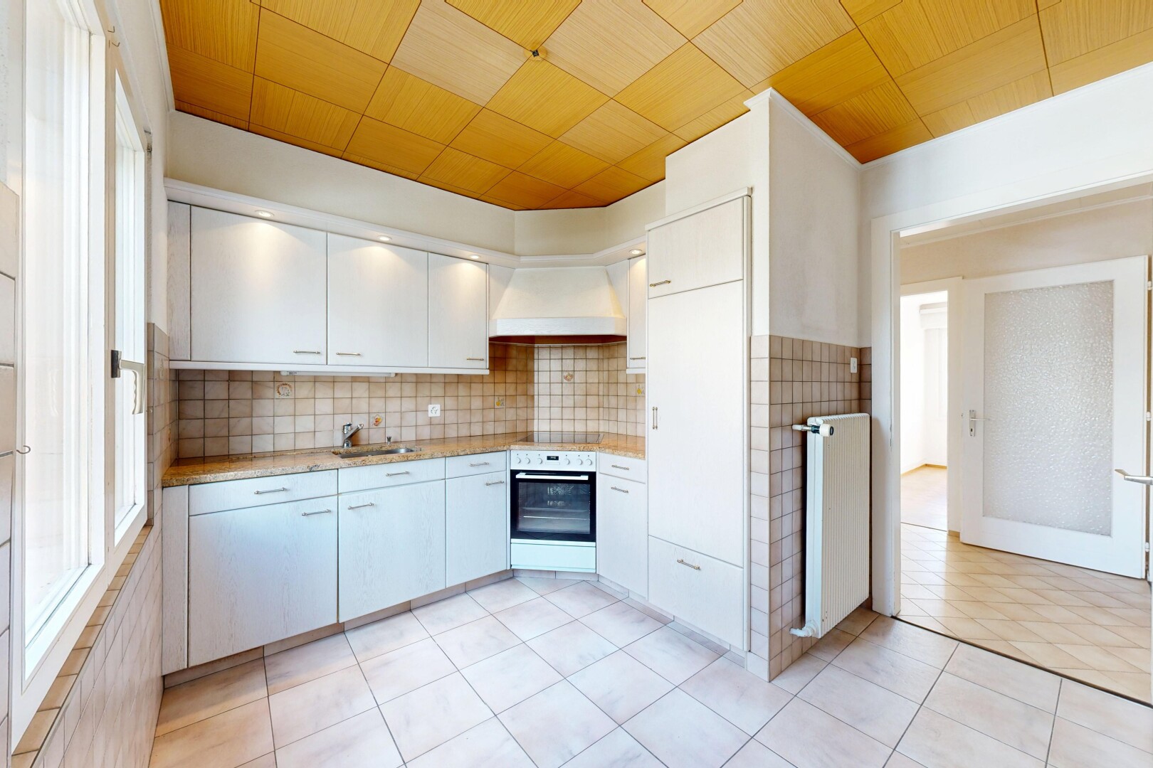 kitchen featuring light countertops, stainless steel oven, radiator heating unit, tasteful backsplash, and light tile patterned floors