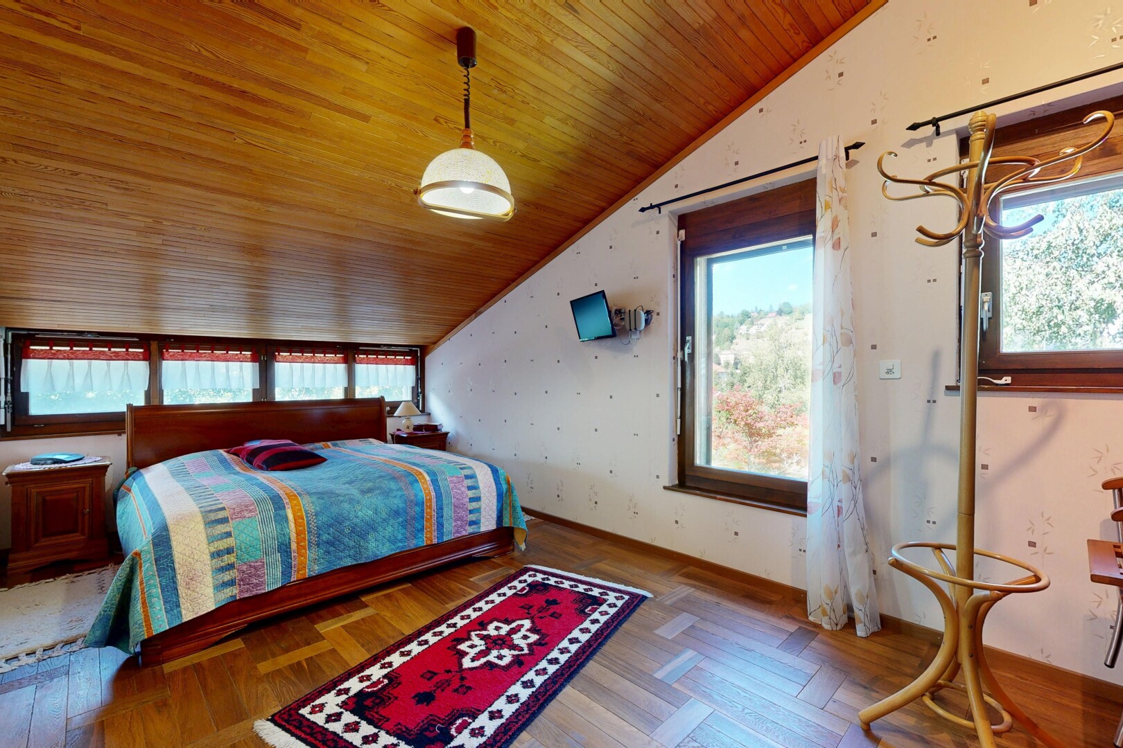 chambre avec vaulted ceiling, plafond voûté, wood finish floor, sol en finition bois, et éclairage suspendu