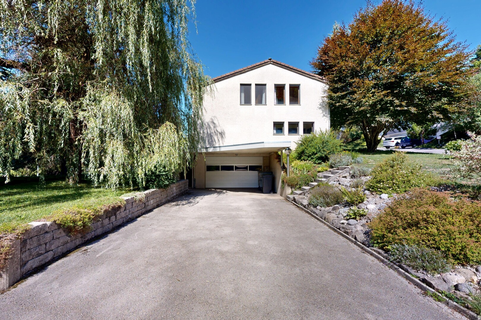 façade avec property visible, allée, garage intégré, bardage en stuc, et garage au sous-sol