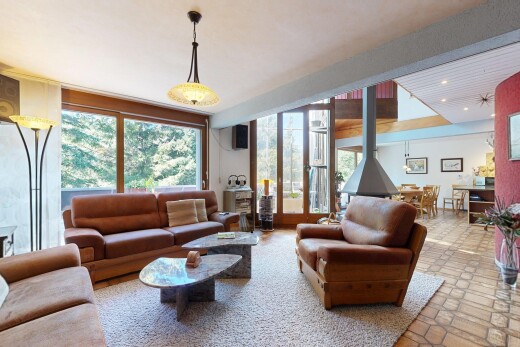 salon avec éclairage suspendu, poêle à bois, inside property, et éclairage encastré