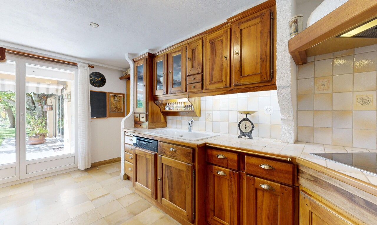 cuisine avec light countertops, hotte, armoires marron moyen, medium brown cabinets, et light floor