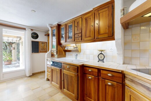 cuisine avec light countertops, hotte, armoires marron moyen, medium brown cabinets, et light floor