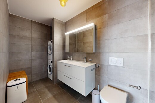 bathroom featuring tile walls, double vanity, stacked washer / drying machine, and dark tile patterned flooring