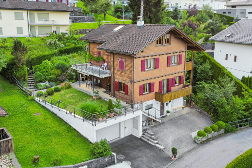 outdoor house with a yard, a chimney, a patio, an attached garage, and driveway