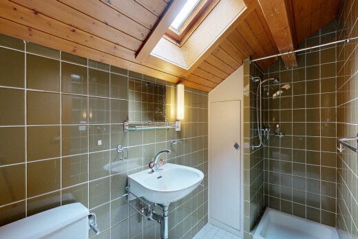 full bath featuring tile walls, a shower stall, a skylight, and a vaulted wooden ceiling