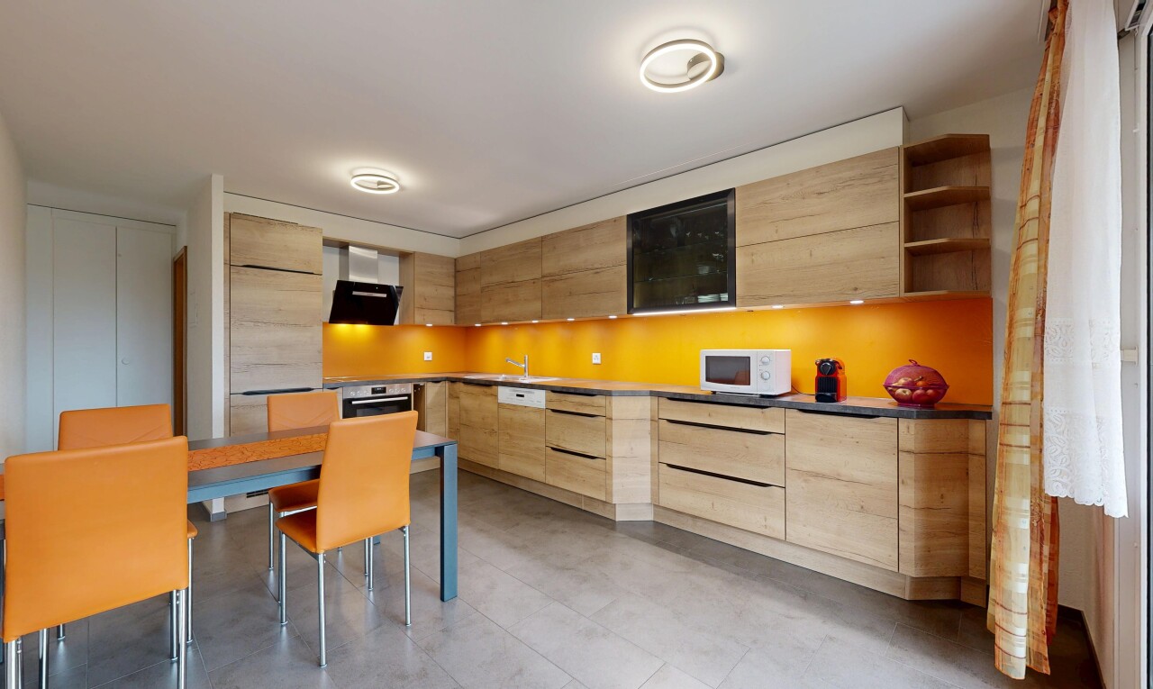 kitchen featuring modern cabinets, open shelves, light brown cabinetry, range hood, and white microwave