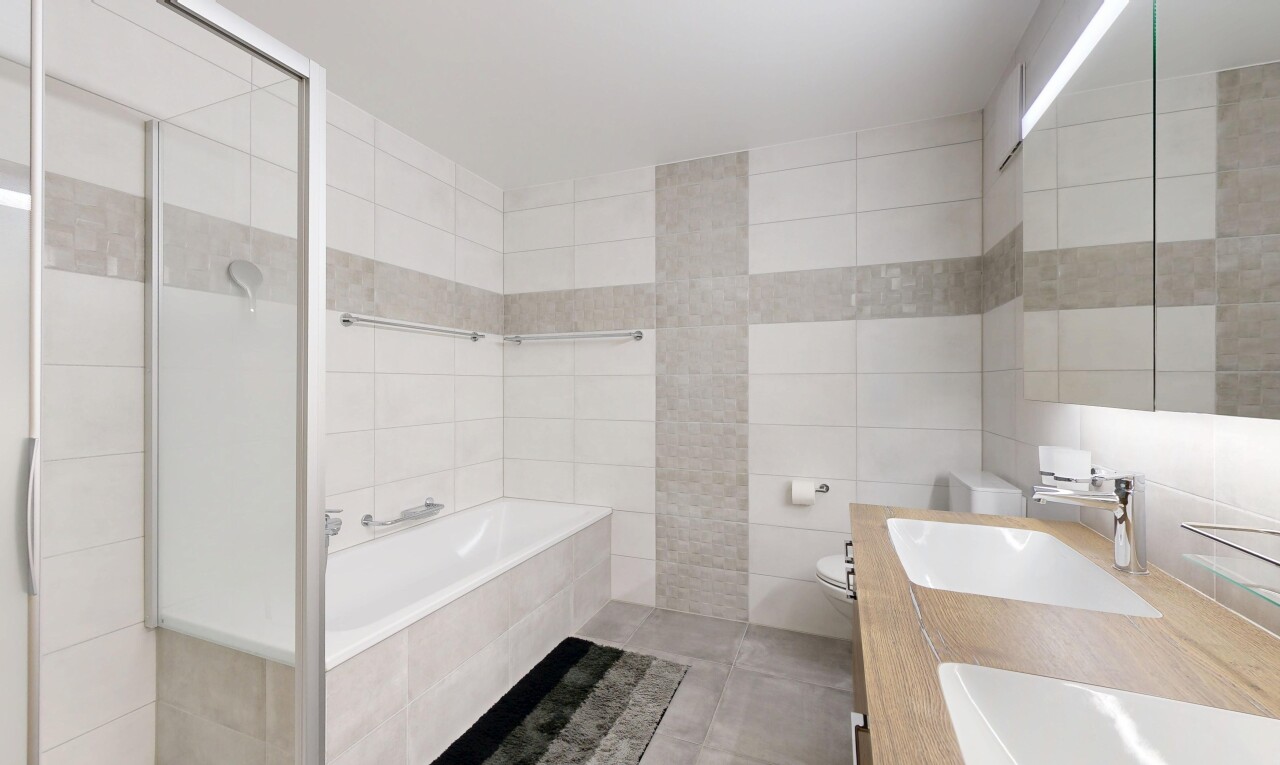 full bathroom with tile walls, a bath, double vanity, tiled shower, and tile patterned floors