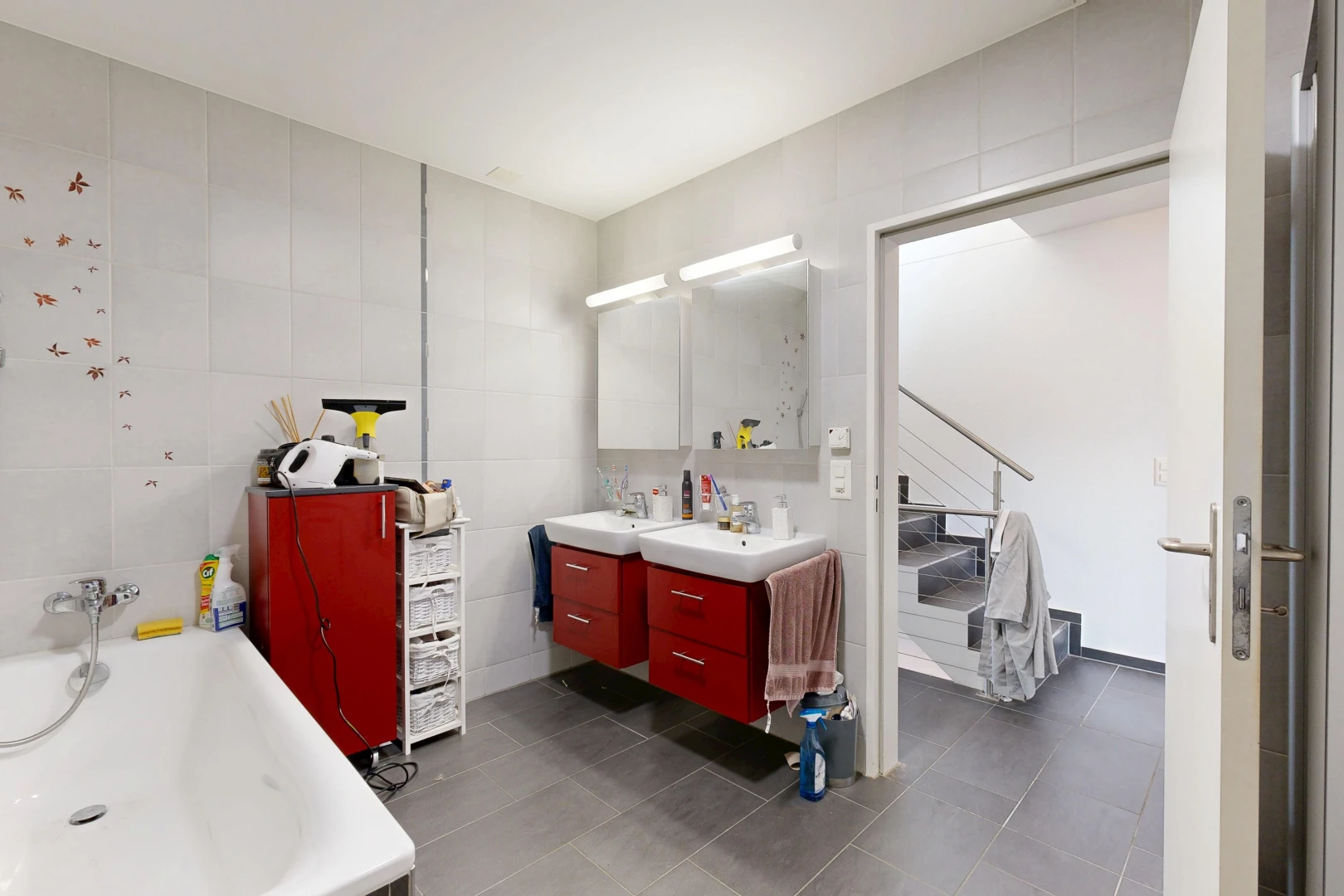 bathroom featuring tile walls, double vanity, a garden tub, and dark tile patterned flooring