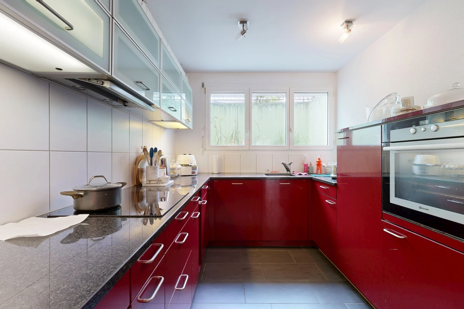 kitchen with stainless steel oven, glass fronted cabinets, dark tile patterned flooring, and black electric stovetop