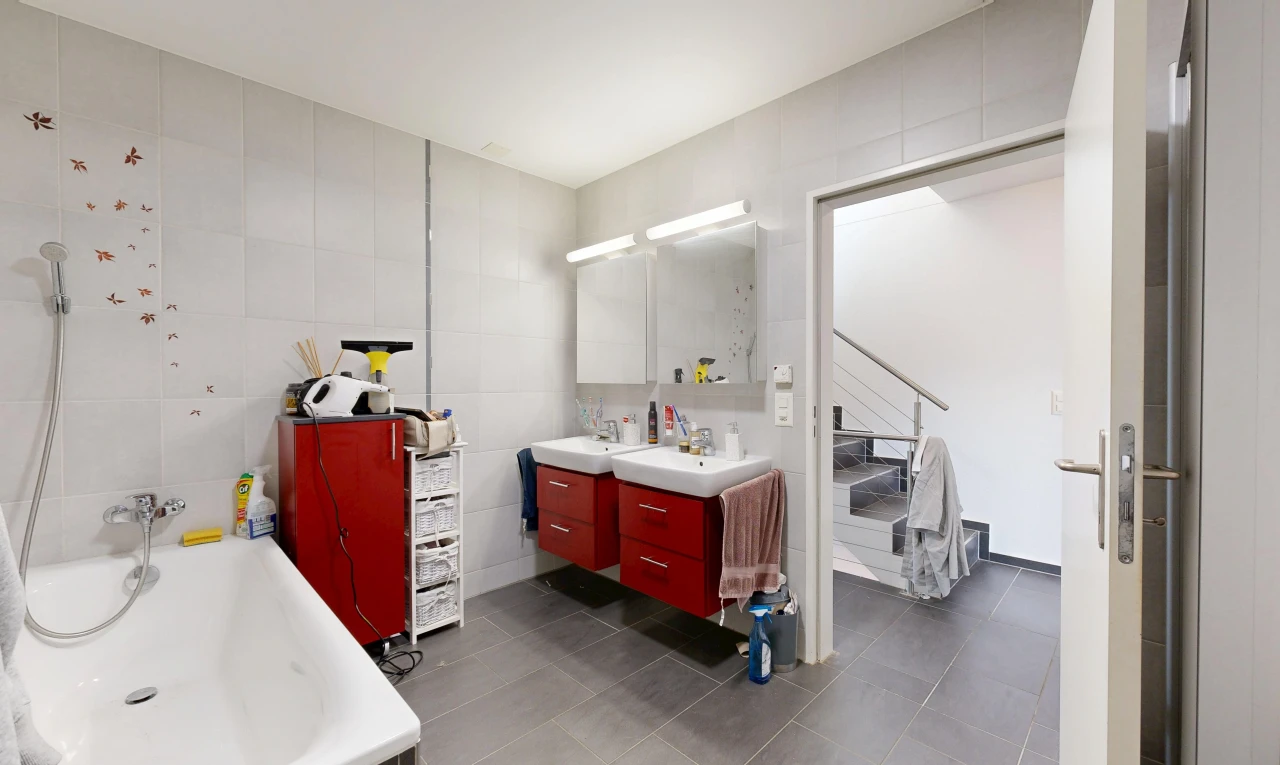 bathroom featuring tile walls, double vanity, a garden tub, and dark tile patterned flooring