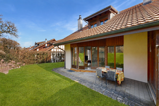 view of property with a chimney, a lawn, a tile roof, and a patio area