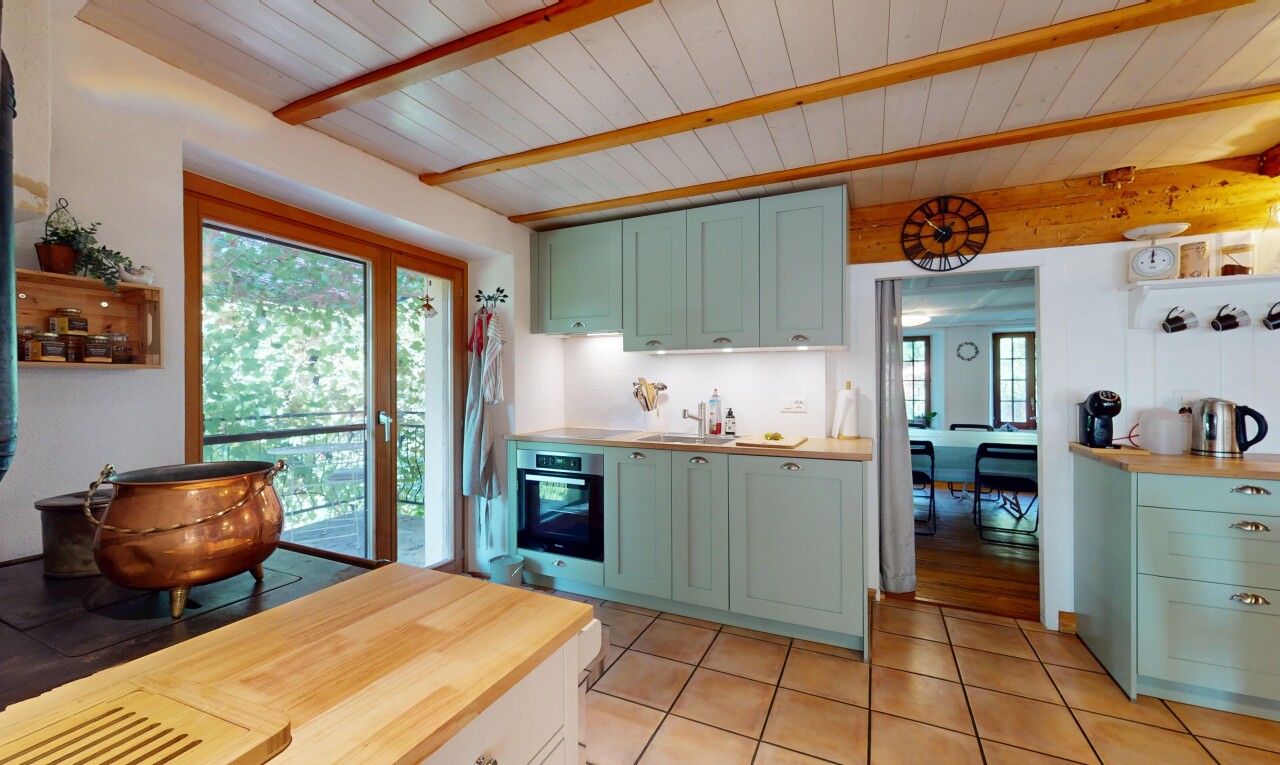 cuisine avec plans de travail en bois de boucher, armoires de style shaker, armoires vertes, inside property, et plafond à poutres