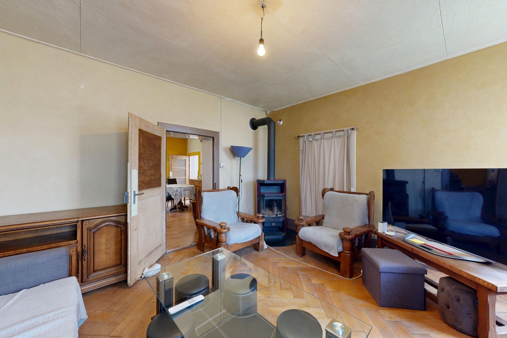 salon / salle à manger avec télévision, poêle à bois, cloison sèche, drywall, et inside property
