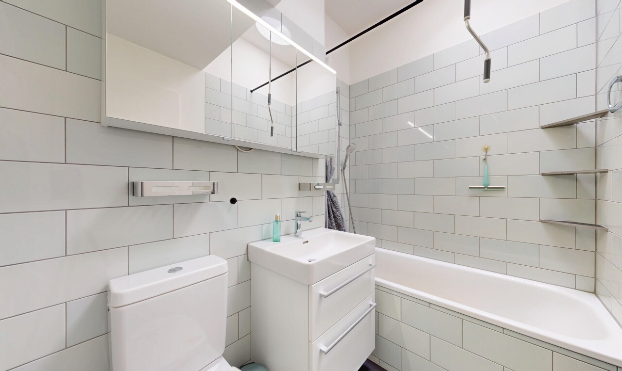 salle de bains avec miroir, lavabo (ou coiffeuse selon le contexte), salle de bain complète, toilette, et douche-bain combinés