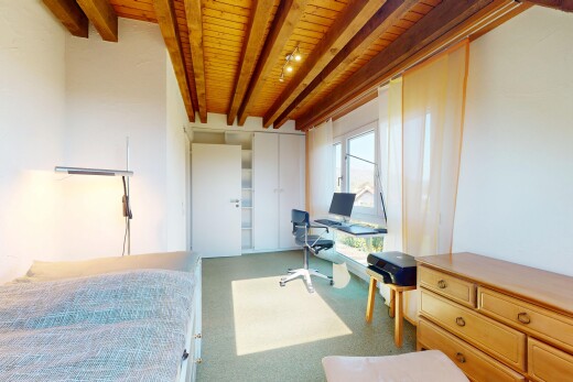 zimmer / schlafzimmer mit balkendecke, holzdecke, bürobereich, fernseher, und teppich