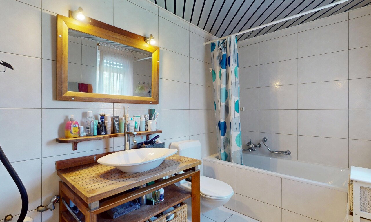 salle de bains avec évier, toilette, miroir, tile shower, et inside property