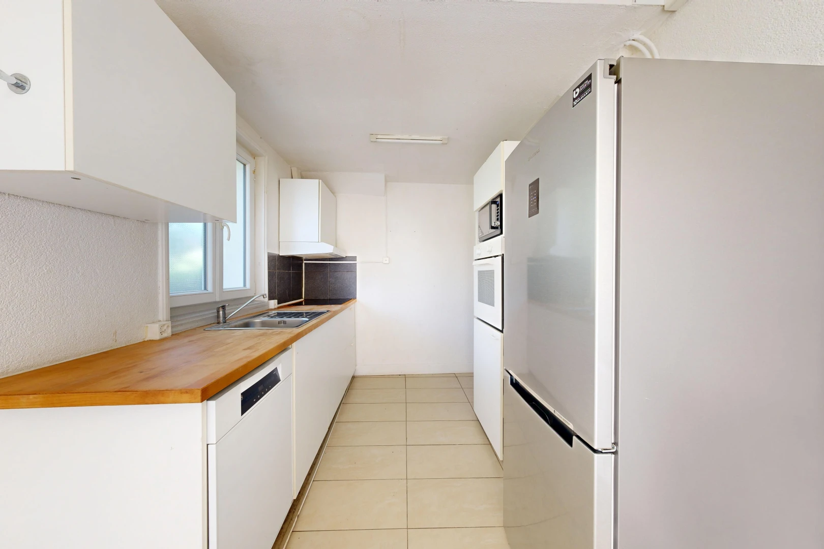 cuisine avec réfrigérateur, butcher block countertops, plans de travail en bois de boucher, light floor, et white cabinets