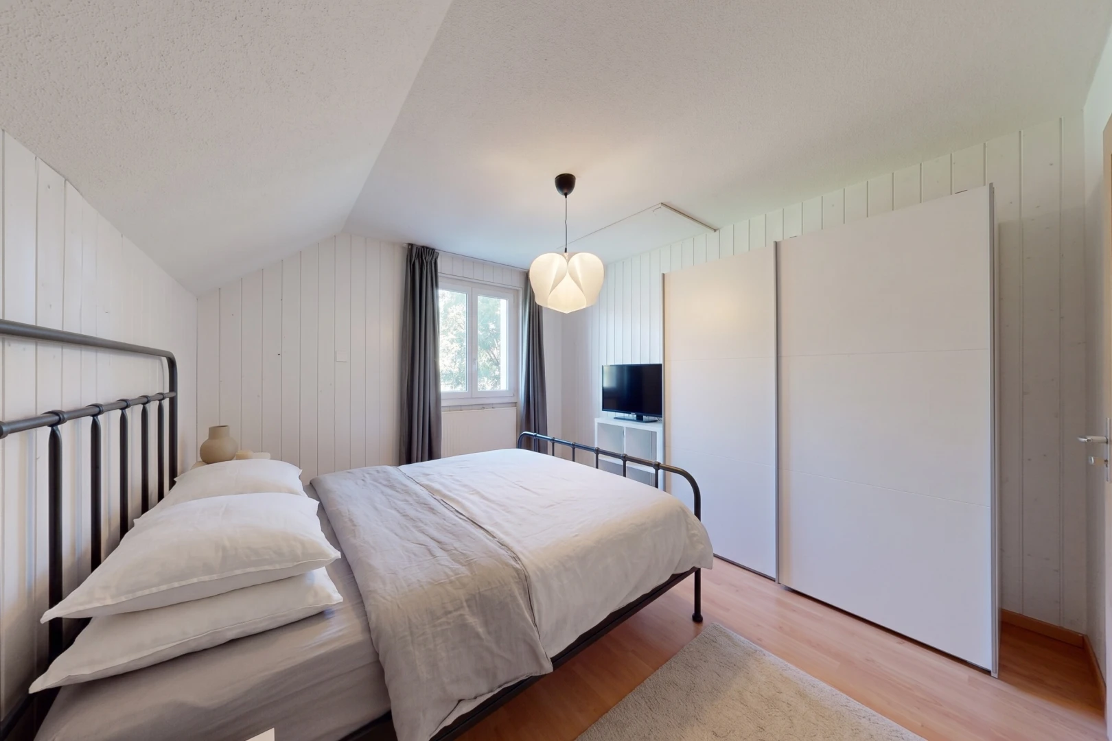 chambre avec vaulted ceiling, plafond voûté, wood finish floor, sol en finition bois, et wood wall