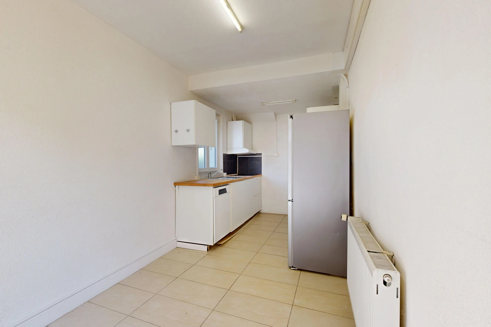 cuisine avec radiateur, réfrigérateur, light floor, armoires blanches, et white cabinets