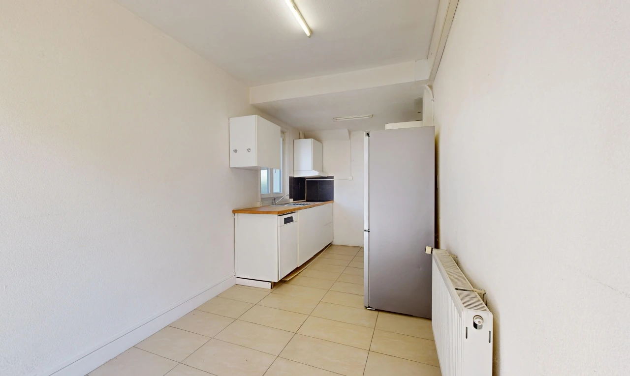 cuisine avec radiateur, réfrigérateur, light floor, armoires blanches, et white cabinets