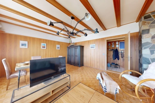 salon avec télévision, plafond à poutres, beamed ceiling, sol en finition bois, et wood finish floor