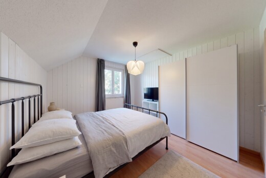 chambre avec vaulted ceiling, plafond voûté, wood finish floor, sol en finition bois, et wood wall