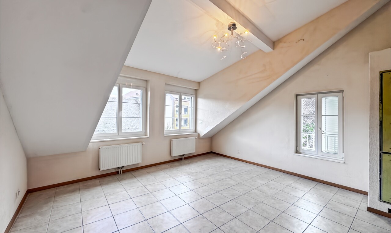 pièce vide avec plafond voûté, vaulted ceiling, plafond à poutres, beamed ceiling, et radiateur